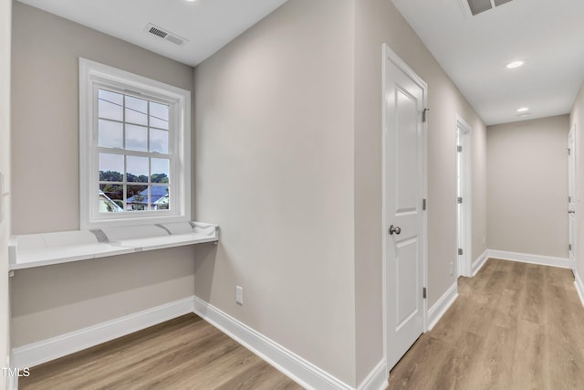 hall featuring light wood finished floors, baseboards, visible vents, and recessed lighting