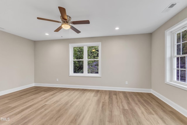 unfurnished room featuring a wealth of natural light, light wood-style flooring, visible vents, and baseboards