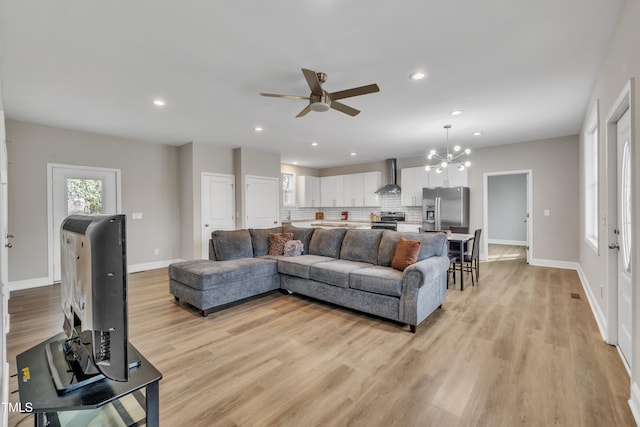 living room with light wood-style floors, ceiling fan with notable chandelier, baseboards, and recessed lighting