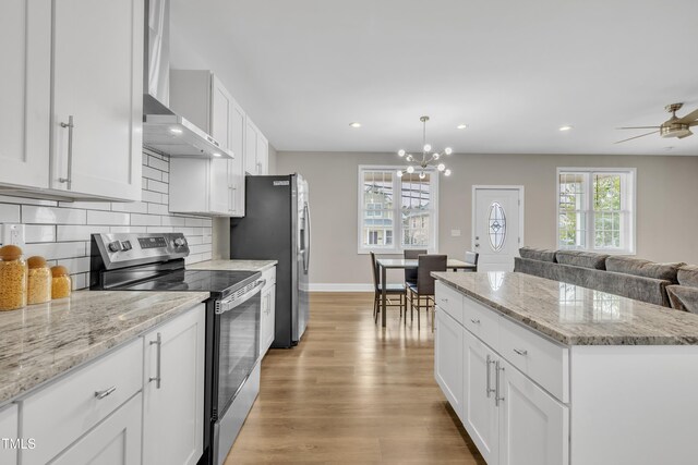 kitchen with appliances with stainless steel finishes, backsplash, wall chimney range hood, and a wealth of natural light