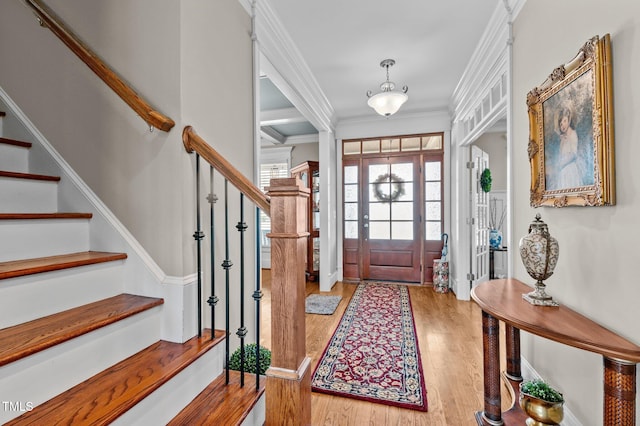 foyer entrance featuring light wood finished floors, stairway, and ornamental molding