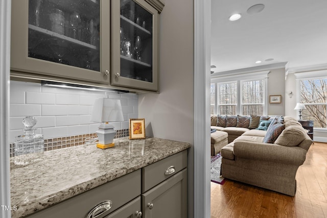 bar featuring recessed lighting, wood finished floors, backsplash, and ornamental molding