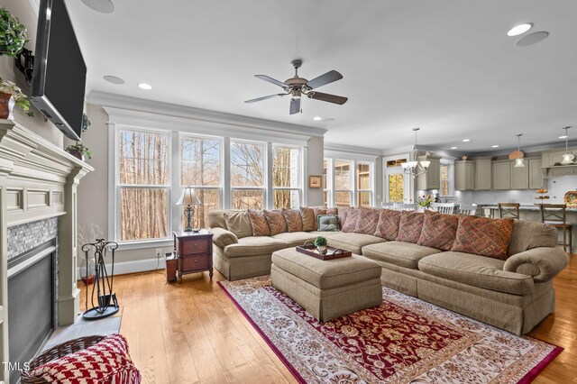 living room with a tiled fireplace, plenty of natural light, and light wood-type flooring