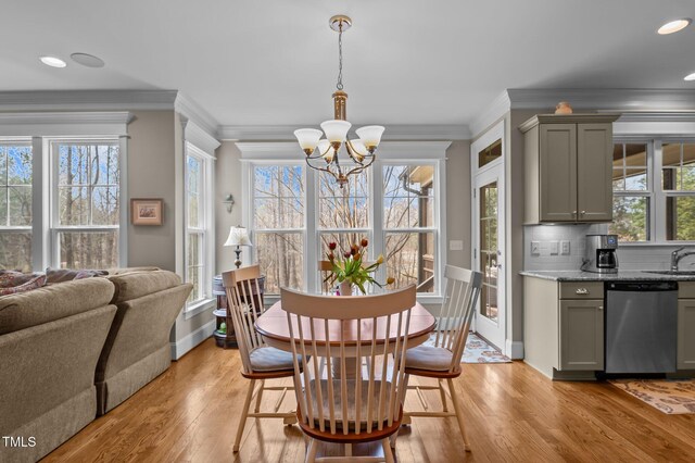 dining space featuring a healthy amount of sunlight, an inviting chandelier, light wood-style floors, and ornamental molding