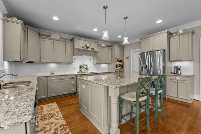 kitchen featuring gray cabinetry, a sink, a kitchen island, appliances with stainless steel finishes, and crown molding