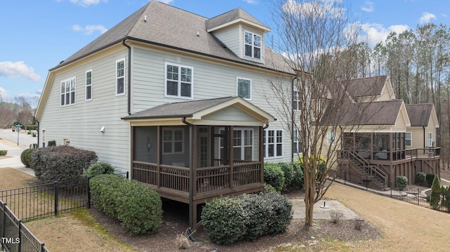 back of property featuring a shingled roof, stairs, a fenced backyard, and a sunroom