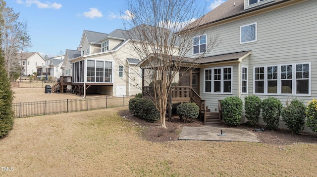 rear view of house featuring stairs, a yard, fence, and a sunroom