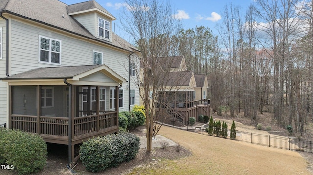 back of house featuring fence, roof with shingles, a sunroom, a wooden deck, and stairs