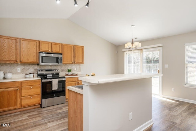 kitchen with tasteful backsplash, light wood finished floors, light countertops, vaulted ceiling, and appliances with stainless steel finishes