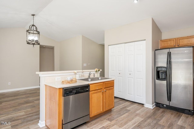 kitchen featuring light wood-style flooring, a sink, stainless steel appliances, light countertops, and vaulted ceiling