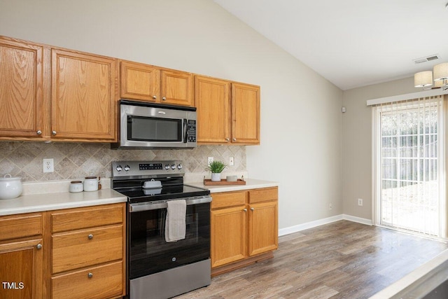 kitchen with stainless steel appliances, visible vents, light countertops, and vaulted ceiling