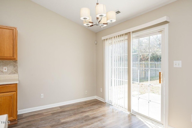 unfurnished dining area with visible vents, baseboards, light wood-style floors, and a notable chandelier