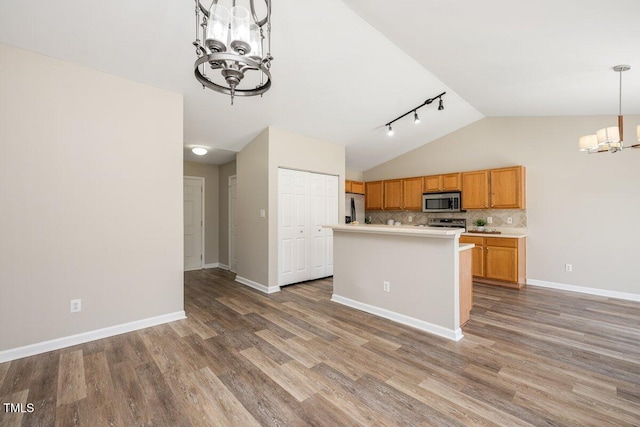 kitchen featuring a chandelier, light countertops, vaulted ceiling, appliances with stainless steel finishes, and wood finished floors