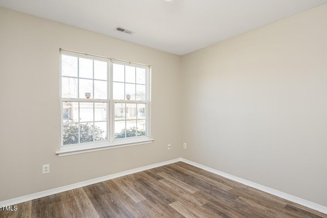 unfurnished room featuring visible vents, baseboards, and dark wood finished floors