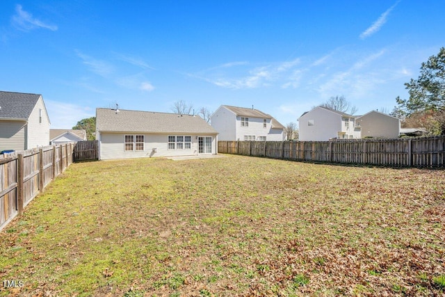 rear view of property featuring a yard and a fenced backyard