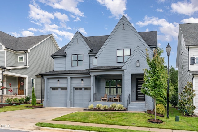 view of front of house featuring covered porch, a garage, a shingled roof, driveway, and a front yard