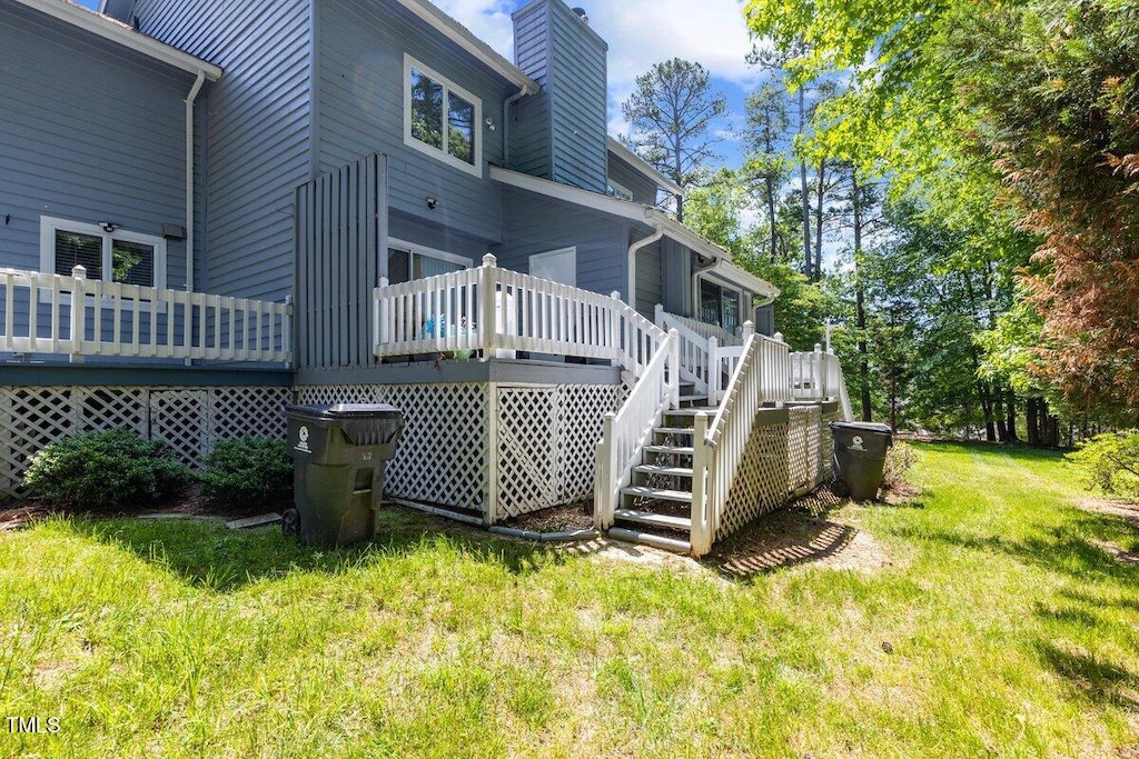 back of property with a yard, stairway, a chimney, and a wooden deck