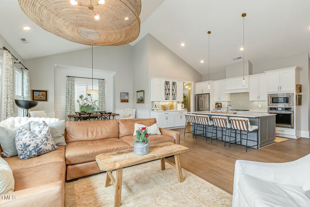 living room featuring visible vents, recessed lighting, high vaulted ceiling, and light wood-type flooring