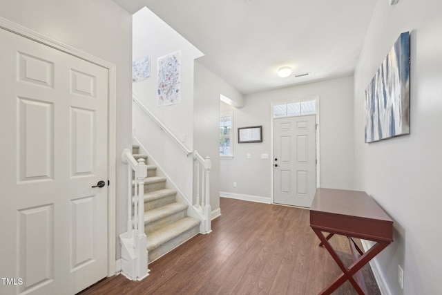 entryway featuring stairway, dark wood-type flooring, and baseboards