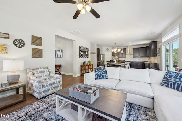 living room featuring baseboards, dark wood-style floors, and ceiling fan with notable chandelier