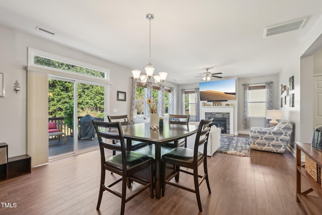 dining space with visible vents, a stone fireplace, and dark wood-style flooring