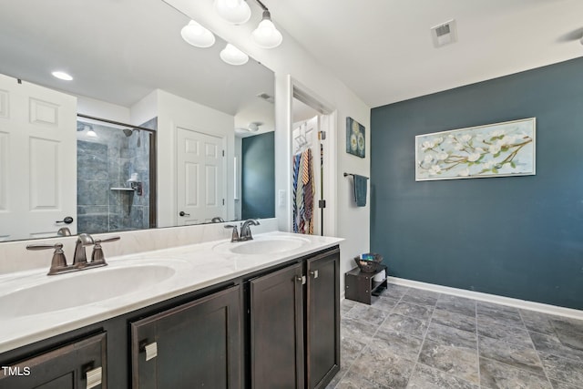 full bath with double vanity, baseboards, a tile shower, and a sink