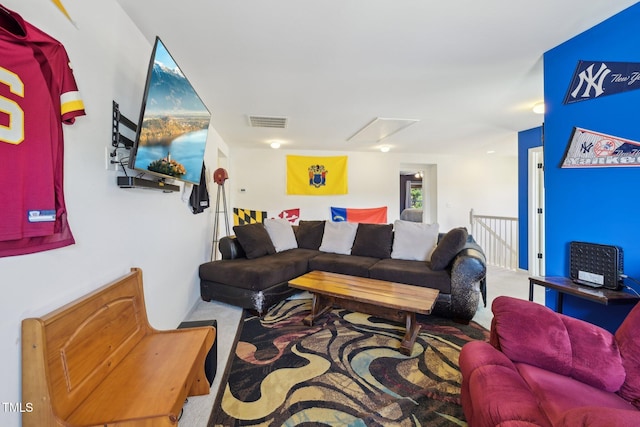 carpeted living room featuring visible vents and attic access