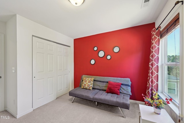 living area with visible vents, baseboards, an accent wall, and carpet flooring