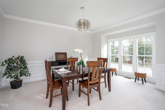 dining area featuring light carpet, visible vents, a wainscoted wall, an inviting chandelier, and crown molding