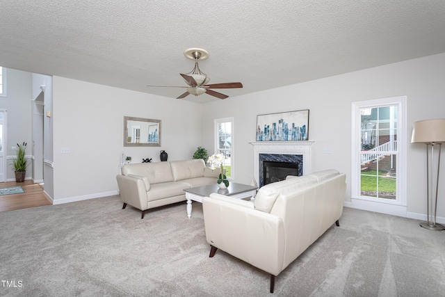 living area featuring light carpet, a textured ceiling, baseboards, and a premium fireplace