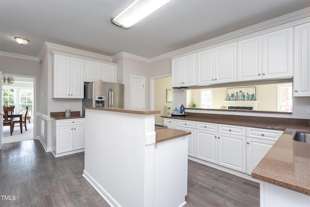 kitchen featuring dark wood-type flooring, a kitchen island, white cabinetry, ornamental molding, and stainless steel fridge