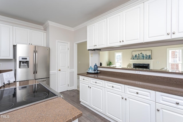 kitchen featuring range with electric cooktop, stainless steel refrigerator with ice dispenser, and white cabinets