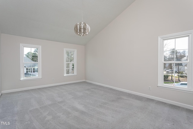 carpeted empty room with baseboards, plenty of natural light, and an inviting chandelier