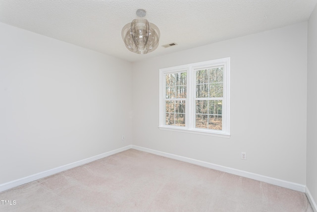 unfurnished room with baseboards, a textured ceiling, visible vents, and light colored carpet