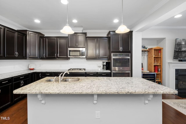 kitchen featuring stainless steel appliances, dark wood-type flooring, a sink, and a breakfast bar area