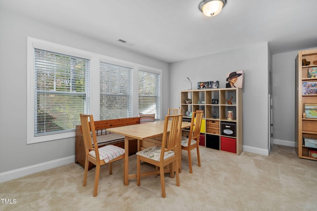 dining room with light carpet, visible vents, and baseboards