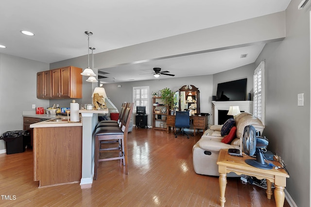 kitchen with light wood-type flooring, open floor plan, light countertops, and a kitchen breakfast bar