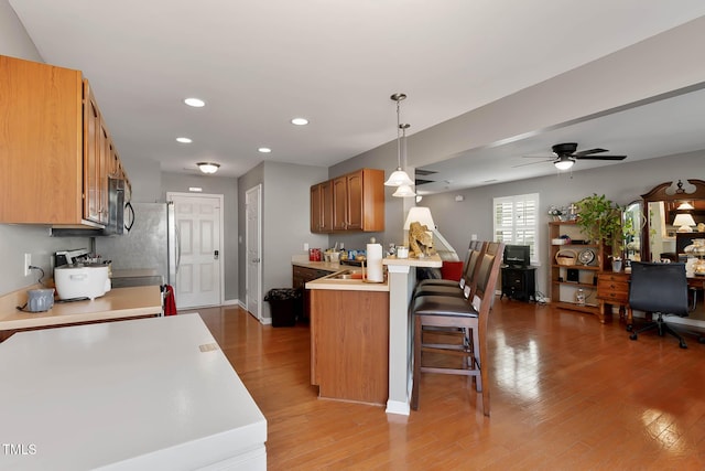 kitchen featuring light countertops, a breakfast bar, stainless steel microwave, and light wood-style flooring