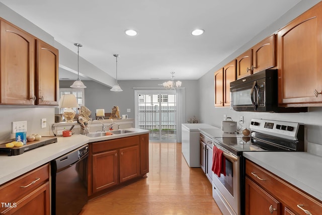 kitchen featuring pendant lighting, light countertops, a sink, and black appliances