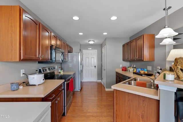 kitchen featuring appliances with stainless steel finishes, light wood-type flooring, light countertops, and a sink