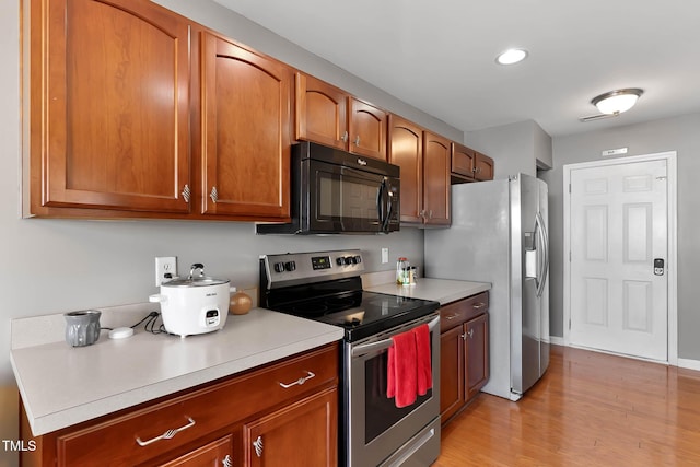 kitchen with light countertops, appliances with stainless steel finishes, brown cabinetry, and light wood-style flooring