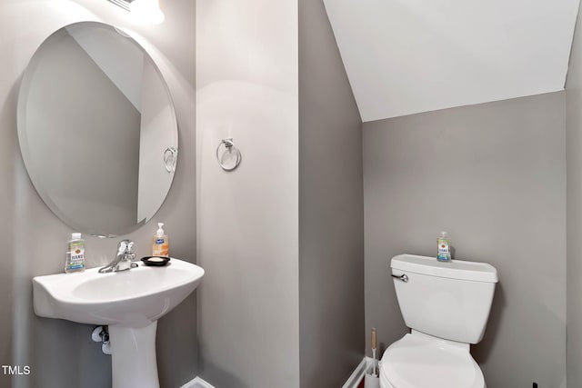 half bath featuring lofted ceiling and toilet