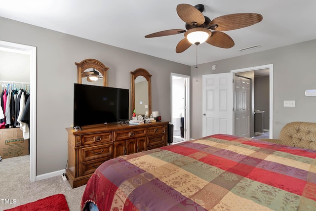 carpeted bedroom with a ceiling fan, visible vents, baseboards, a closet, and a walk in closet