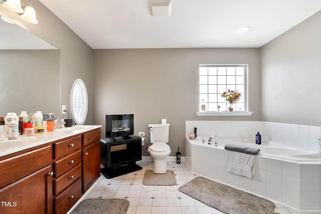 bathroom featuring toilet, a sink, visible vents, a bath, and double vanity