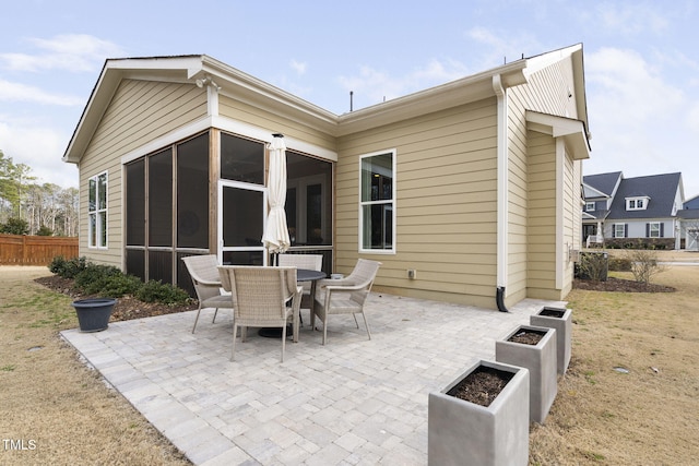 view of patio with a sunroom, fence, and outdoor dining area