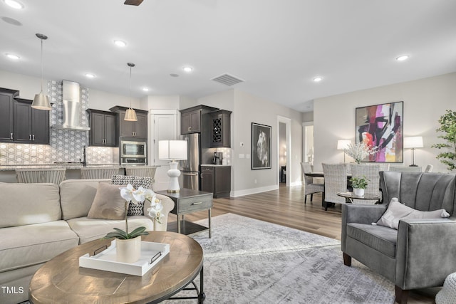 living area with visible vents, baseboards, wood finished floors, and recessed lighting