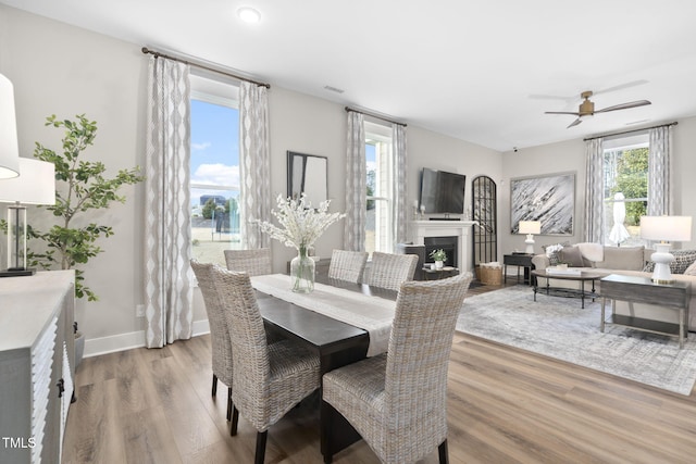 dining space with light wood-style floors, visible vents, a fireplace, and baseboards