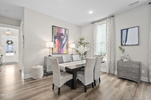 dining area featuring a chandelier, visible vents, baseboards, and wood finished floors