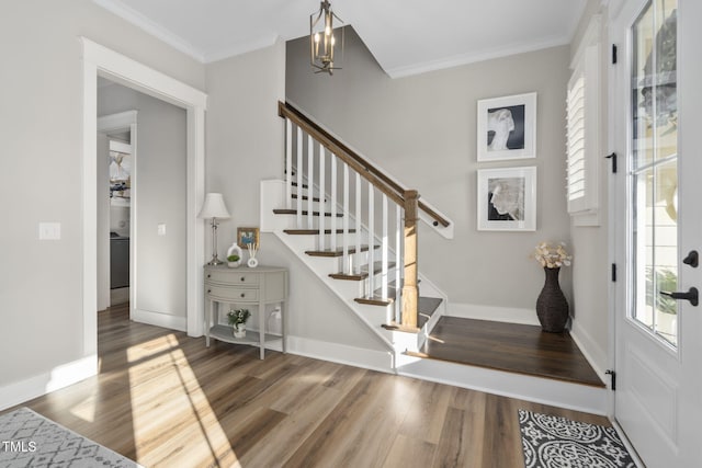 foyer entrance with crown molding, stairs, baseboards, and wood finished floors