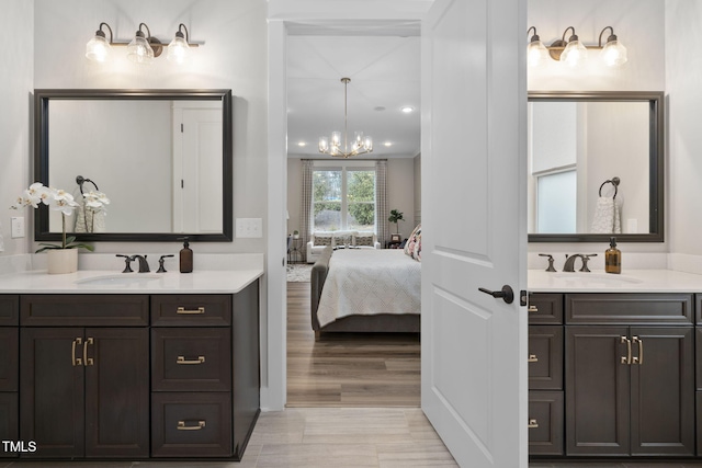 ensuite bathroom with a notable chandelier, connected bathroom, two vanities, and a sink